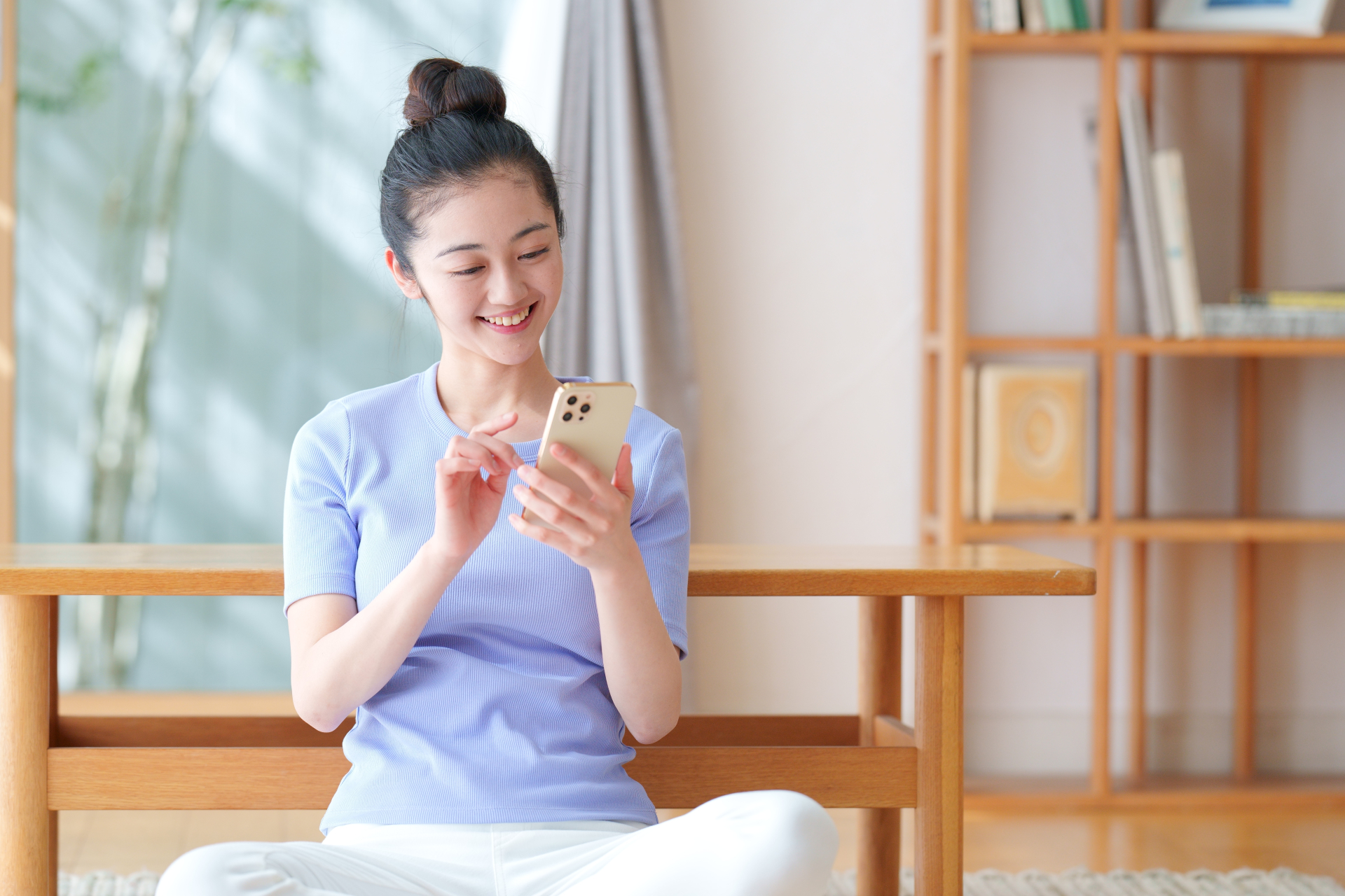 明るい室内でスマートフォンを使う女性