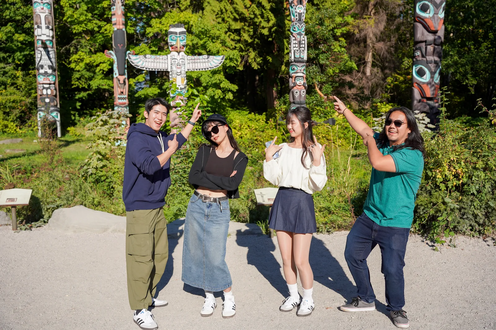 トーテムポールのある公園でポーズをとる4人